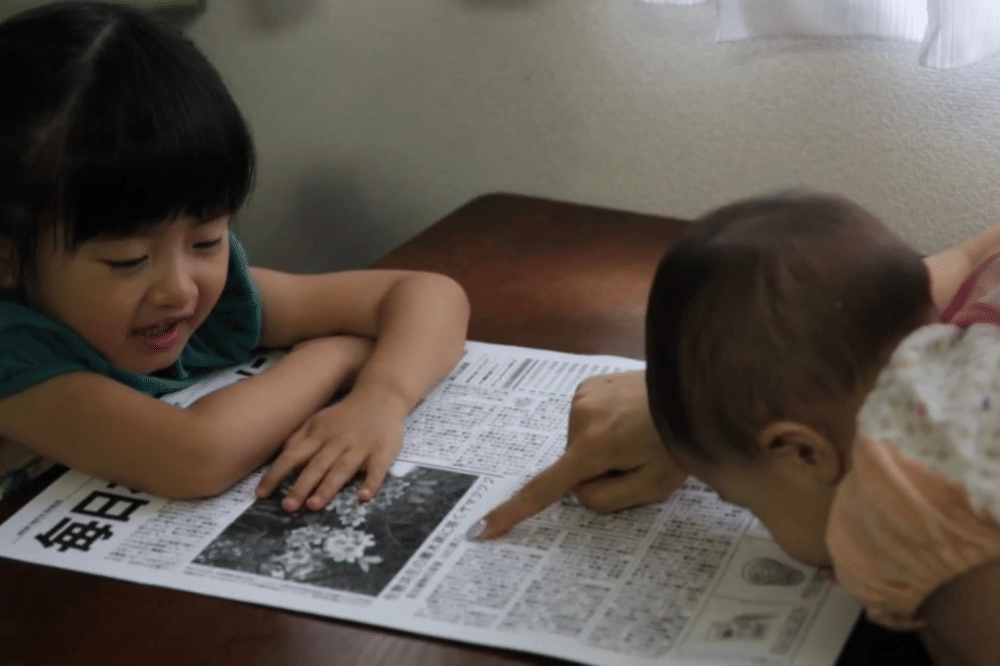 seoang anak sedang membaca koran