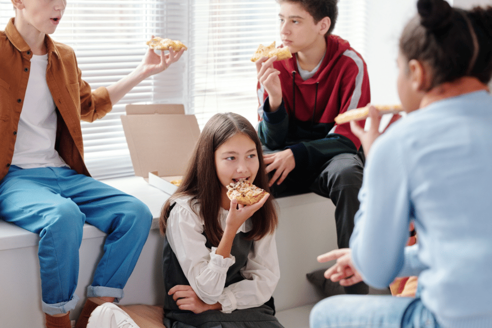 Anak anak sedang makan pizza bersama