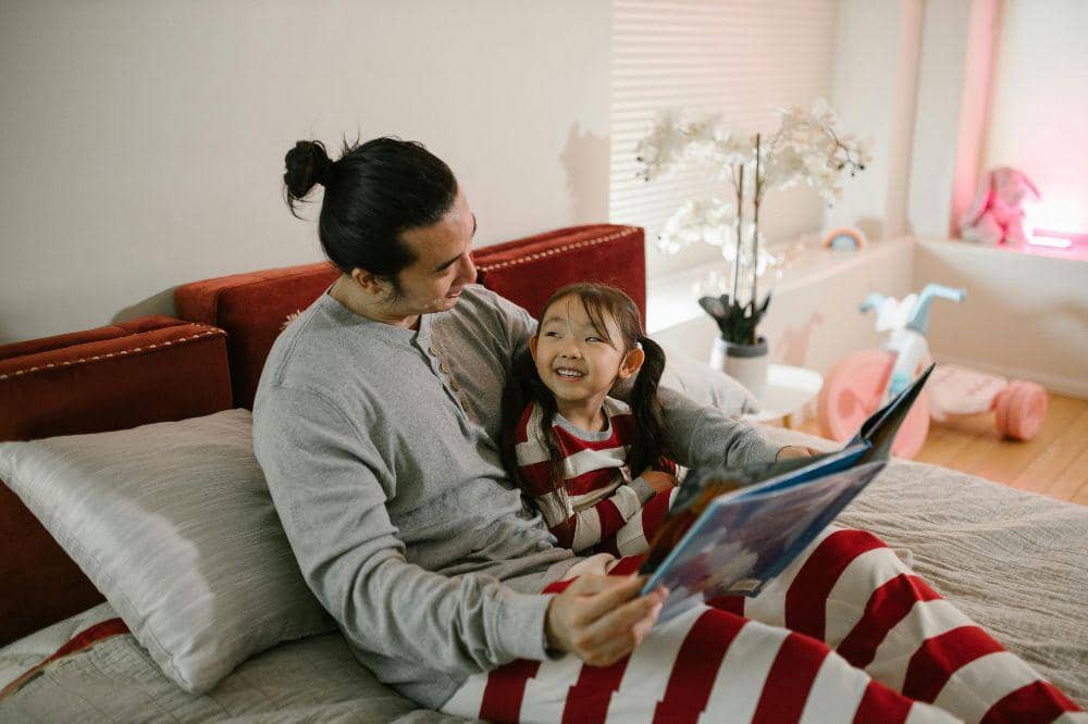Papa membacakan buku cerita agar anak tidur teratur