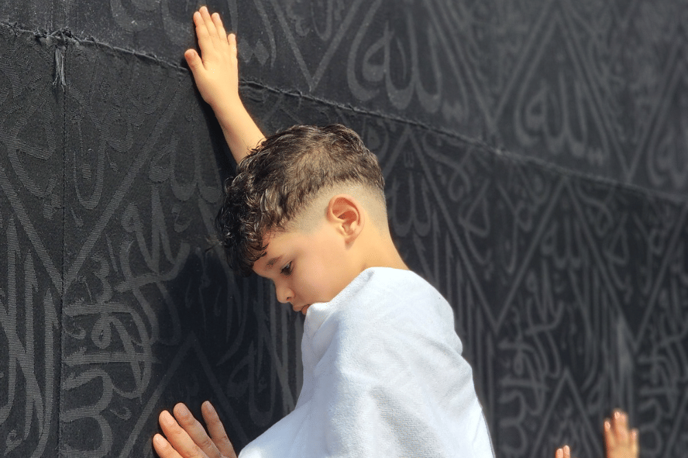 Seorang anak memegang kaabah saat ibadah umroh 