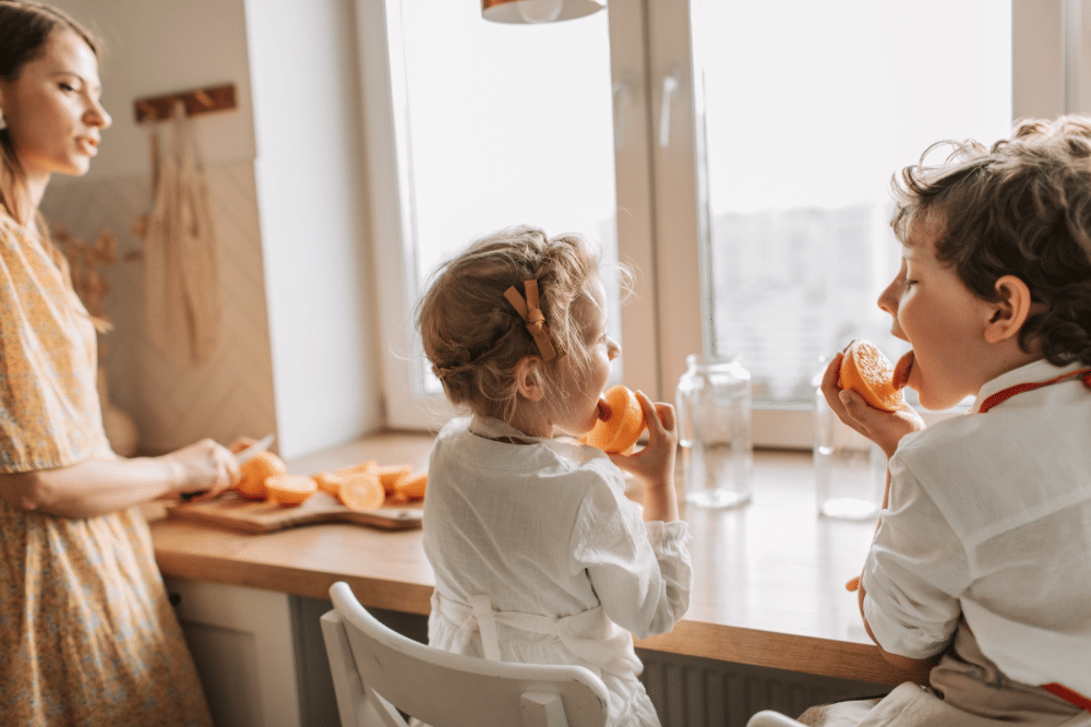 Dua orang anak sedang makan jeruk 