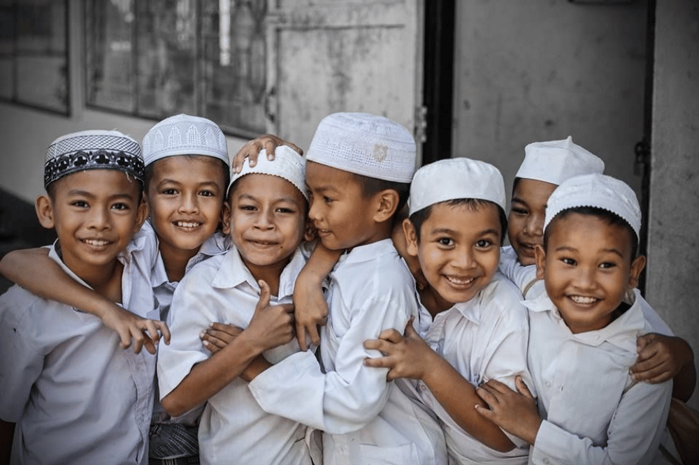 Anak-anak mengenakan peci berpose di depan kamera 