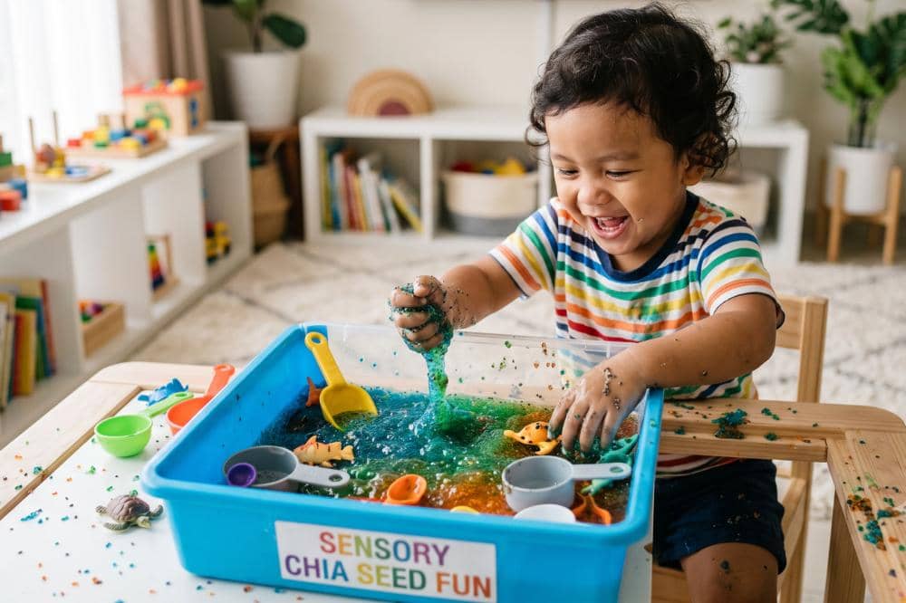 Memainkan ocean sensory bin menggunakan chia seed anak terlihat bahagia