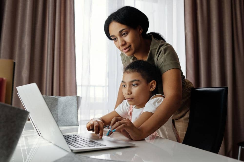 Mama membantu anak mencari informasi internet di laptop