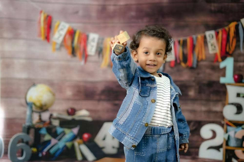 Anak dengan bahagia dan percaya diri mengingat huruf pada balok mainan