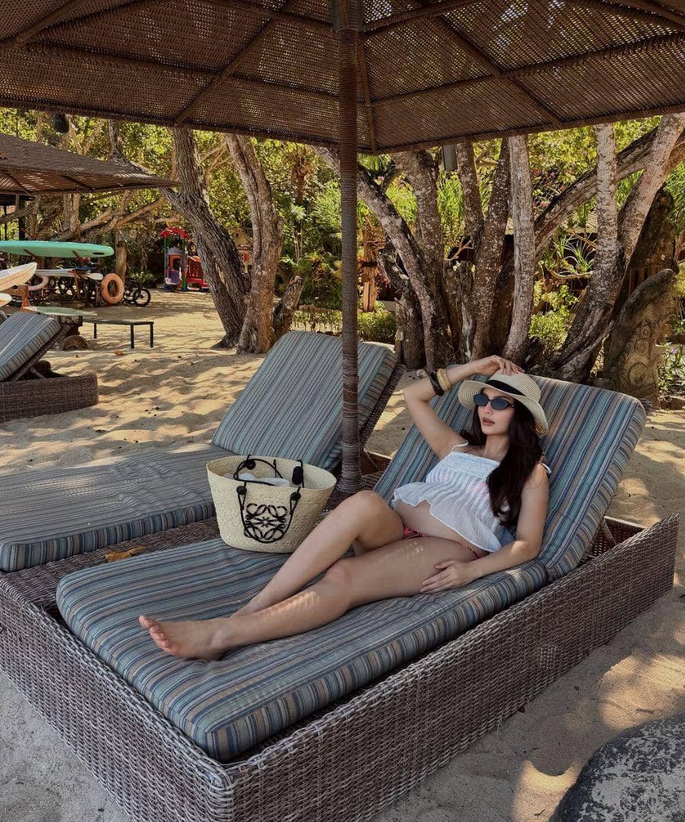Bersantai di kursi pantai sambil menunjukkan baby bump