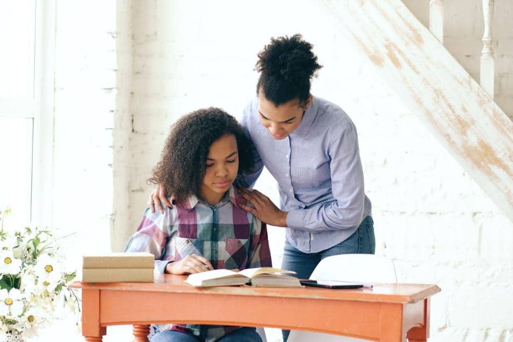 Mama sedang membantu anak dalam pemahaman pada buku yang sedang dibaca