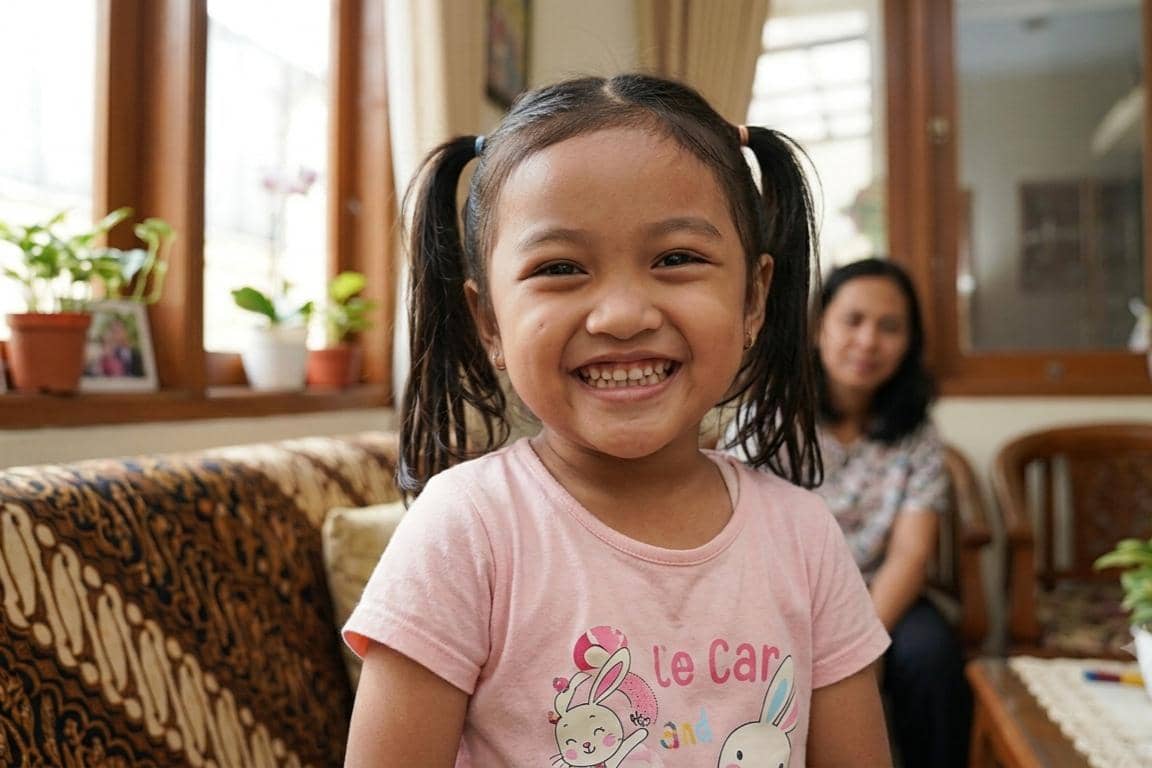 Anak menunjukkan deretan giginya pada kamera sembari tersenyum