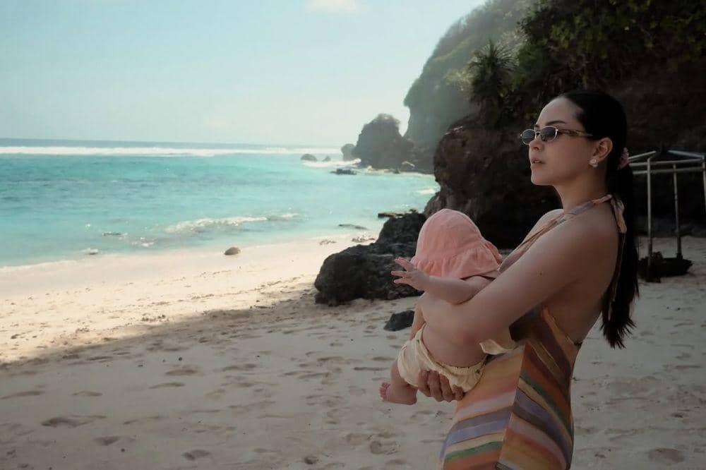 Alyssa gendong Soleil sambil menikmati view pantai