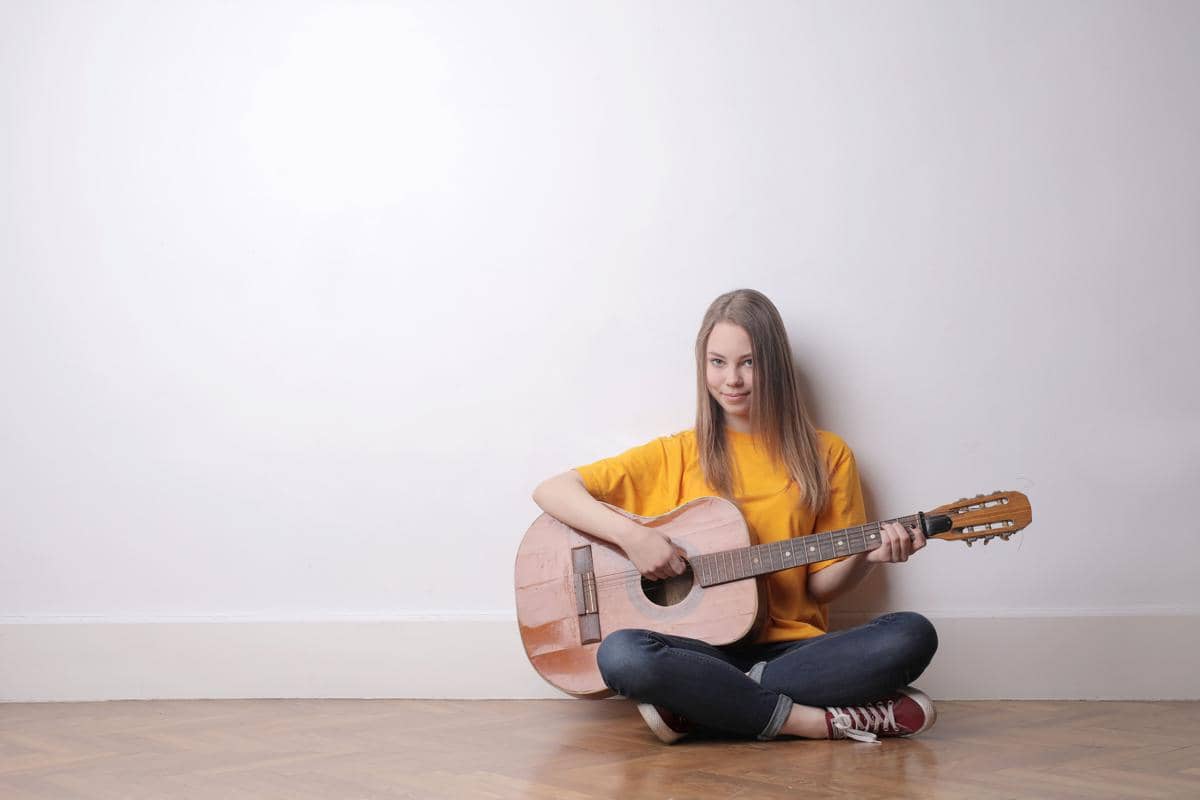 Anak remaja perempuan sedang memainkan gitar 