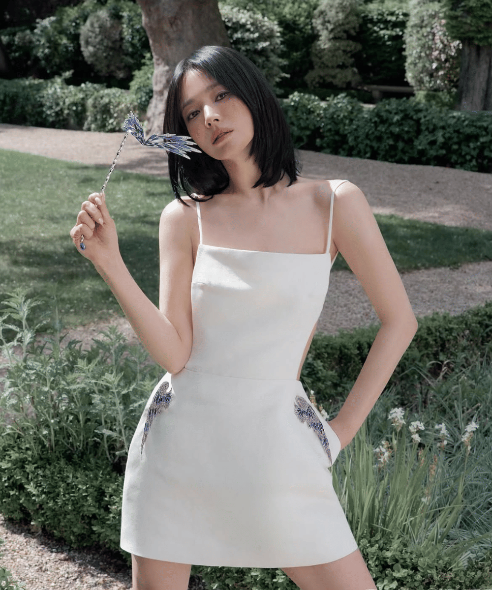 Mini dress putih bertali tipis dengan detail bordir bernuansa seni
