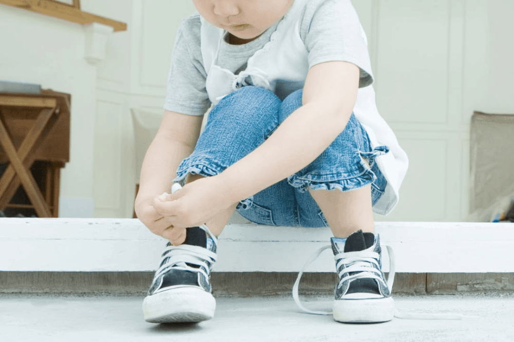 Anak sedang mengikat tali sepatunya