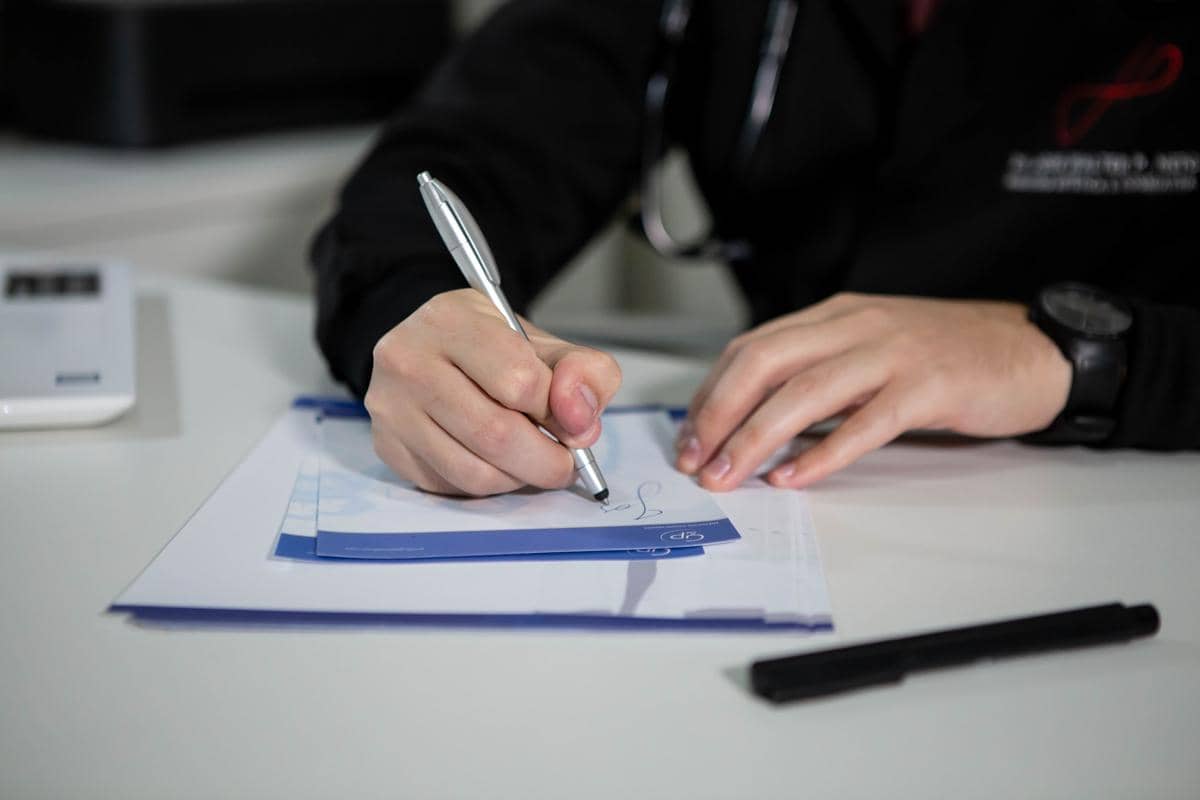 Tangan dokter sedang menulis resep pada kertas.