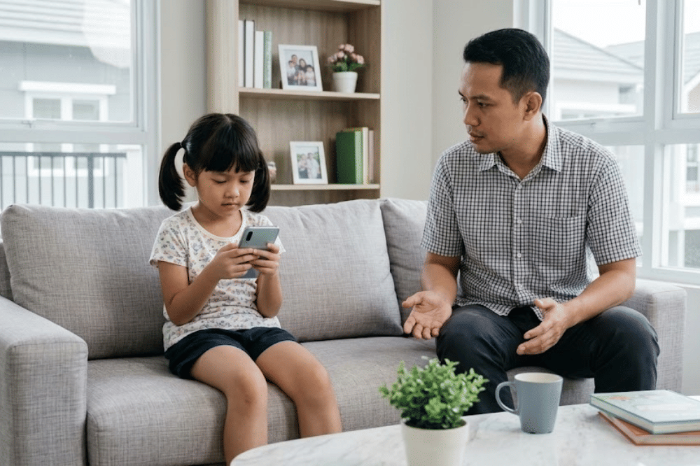 Anak yang sedang bermain handphone dan mendiamkan papanya