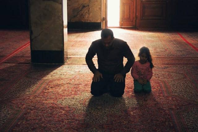 Anak perempuan mengikuti Papa yang sedang salat