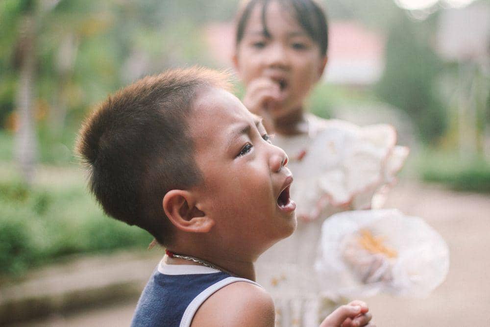 Anak laki-laki menangis melihat kakak memakan sesuatu